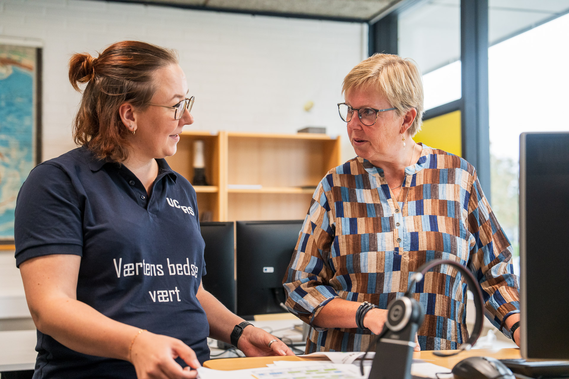 Kvinde og elev arbejder sammen ved skrivebord
