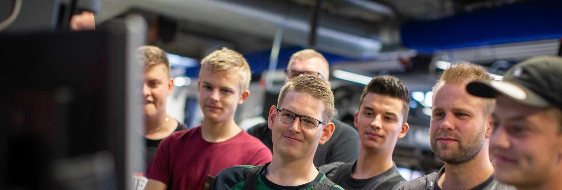 Gruppe af unge mænd står side om side i et værksted