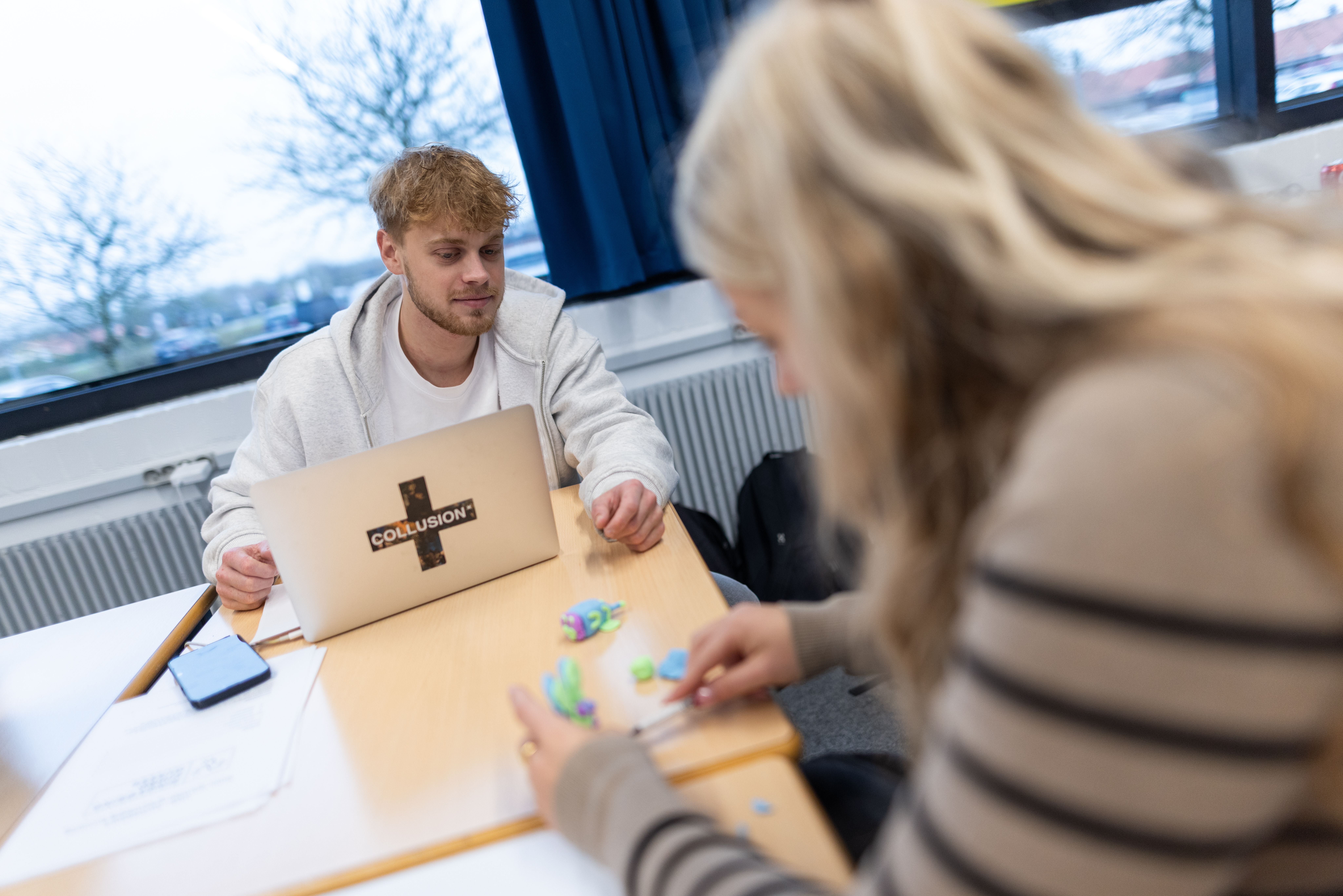 Ung mand i butiksuniform betjener en kunde ved disken