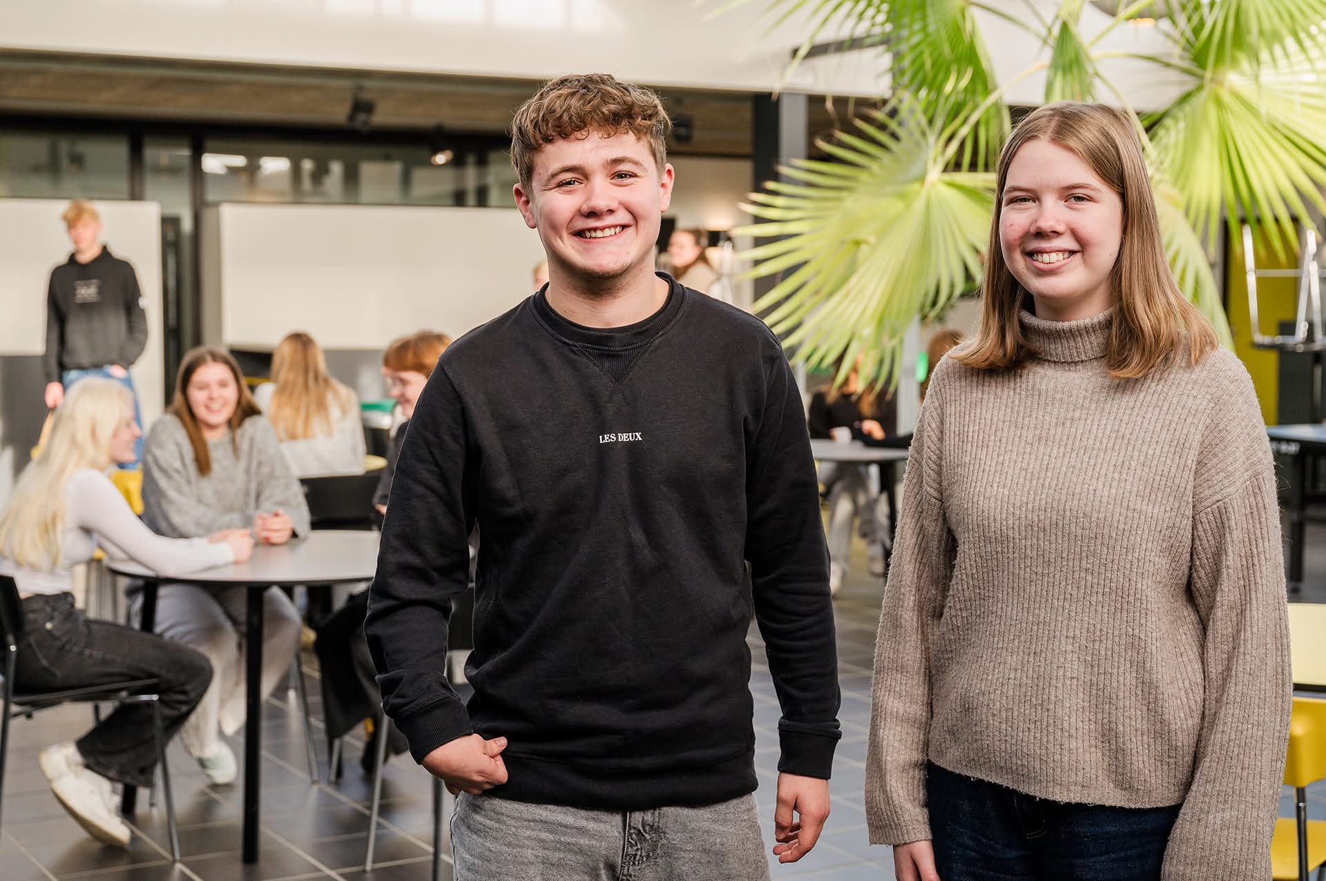 To elever står og smiler sammen