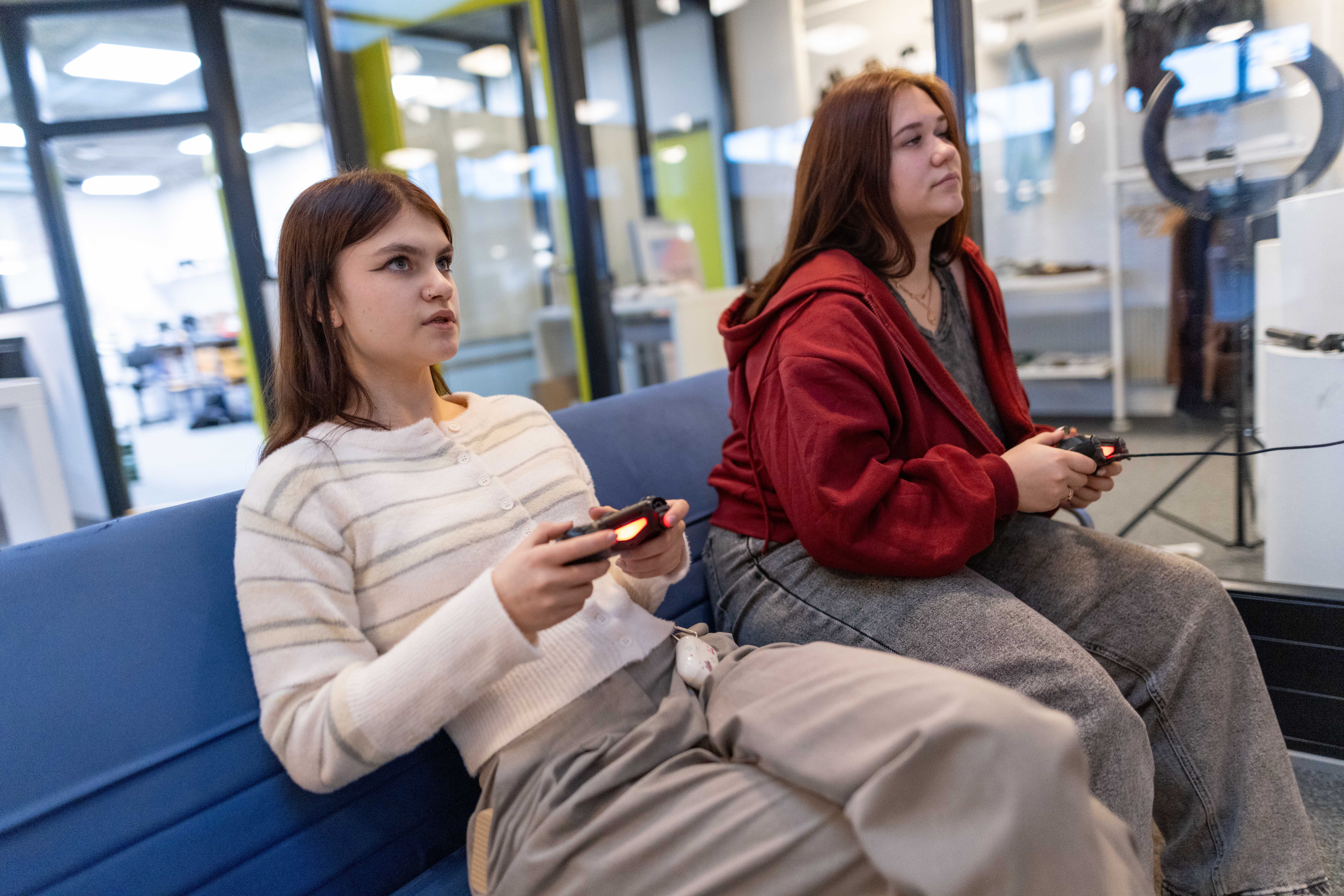 To unge kvinder sidder sammen og kigger på deres telefoner