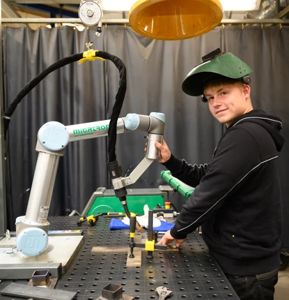 Ung person arbejder med en robotarm i et værksted